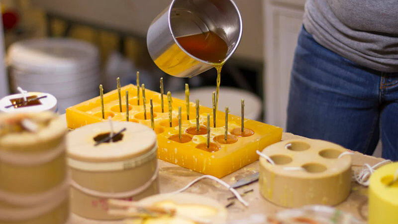 Pouring melted beeswax into mini candle molds