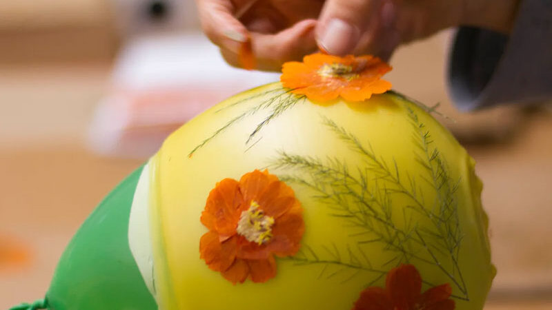 Decorating a newly-dipped beeswax lantern with papier-mâché flowers