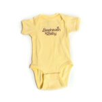 Yellow baby onesie with brown text reading, "Beehaven Baby", adorned with two small bee illustrations.